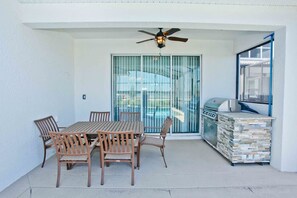 A covered patio with a table and chairs, a ceiling fan, and a barbecue grill. - Private Pool 5 bed/5 bath home inside Resort (Kissimmee)