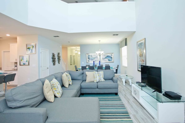 A modern living room with a sectional sofa, a glass coffee table, and a flat-screen TV.