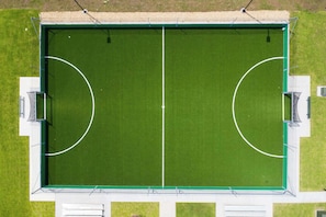 An aerial view of a rectangular sports field with two goal areas, surrounded by a white boundary and green field.