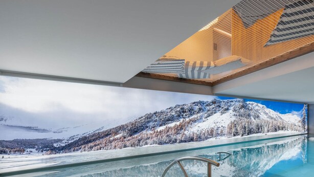 Una piscina interior moderna con vistas a un paisaje montañoso nevado.