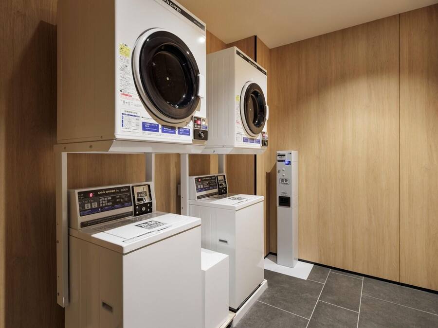 Una sala de lavandería con dos lavadoras de carga frontal y un panel de control.