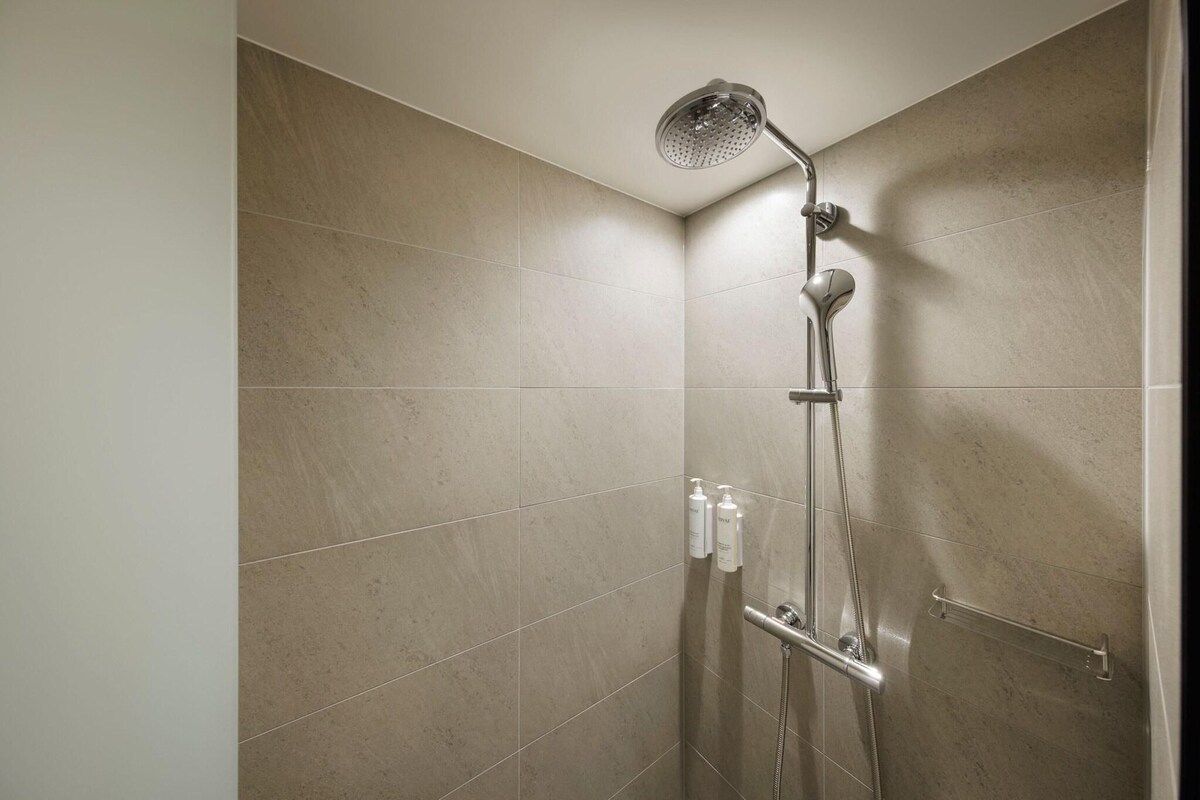 A shower with a handheld showerhead, a handheld showerhead, and a handheld showerhead.