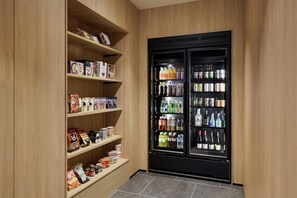 A storage area with wooden shelves and a black beverage refrigerator. - Fairfield By Marriott Kumamoto Aso (Aso)
