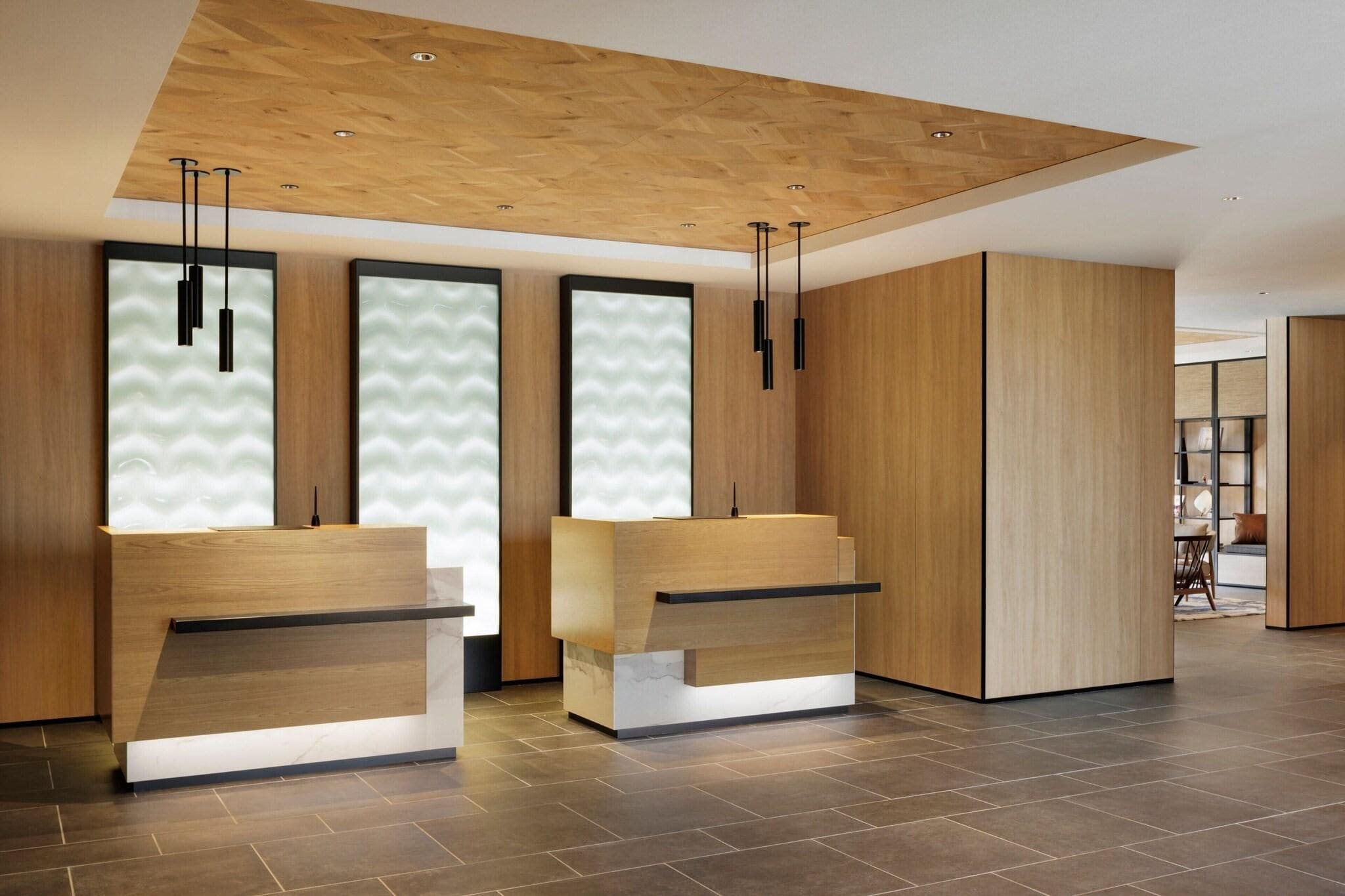 A reception area with two wooden reception desks, a wooden ceiling, and a tiled floor.
