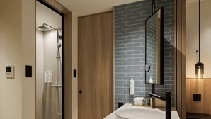 A modern bathroom with a shower, a sink with a mirror, and toiletries on the counter.
