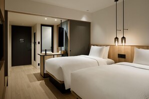 A modern hotel room with two beds, a wooden headboard, a bedside table, and a mirror. - Fairfield By Marriott Kumamoto Aso (Aso)
