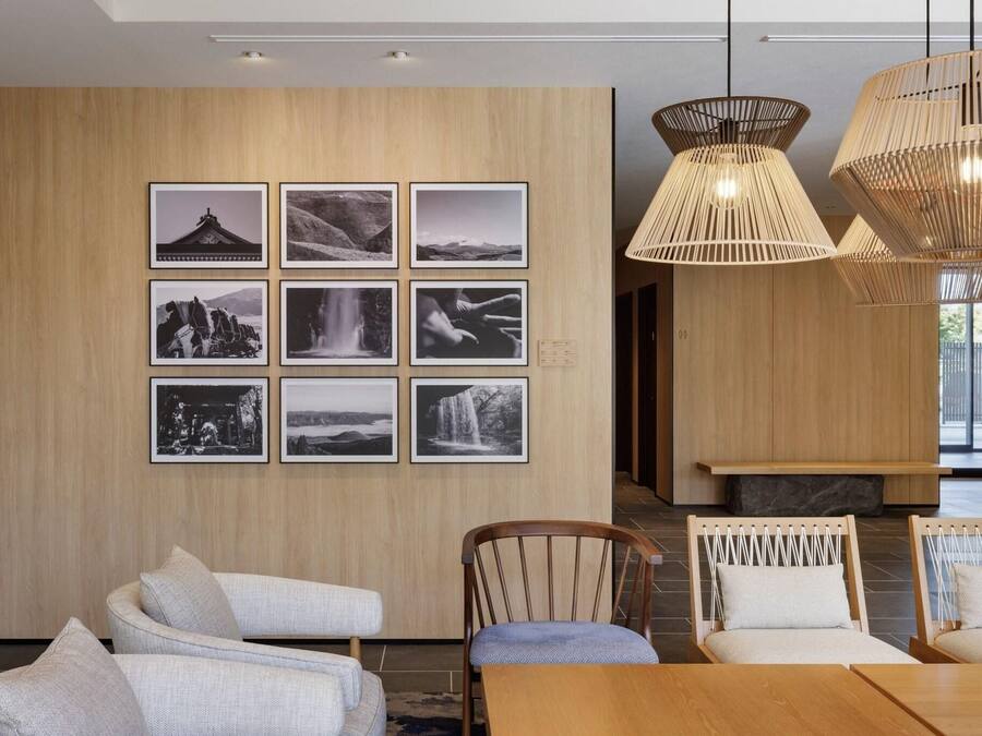A modern dining area with wooden panel walls, a series of black and white photographs, and a wooden dining table with chairs.