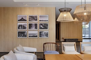 A modern dining area with wooden panel walls, a series of black and white photographs, and a wooden dining table with chairs.