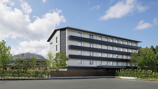 A multi-story hotel with a flat roof and a modern design, featuring a large parking area in front. - Fairfield By Marriott Kumamoto Aso (Aso)