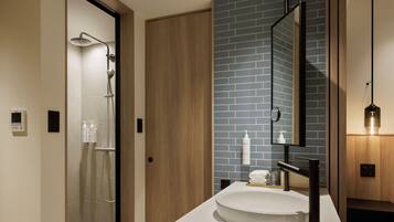 A modern bathroom with a shower, a sink with a mirror, and toiletries on the counter.