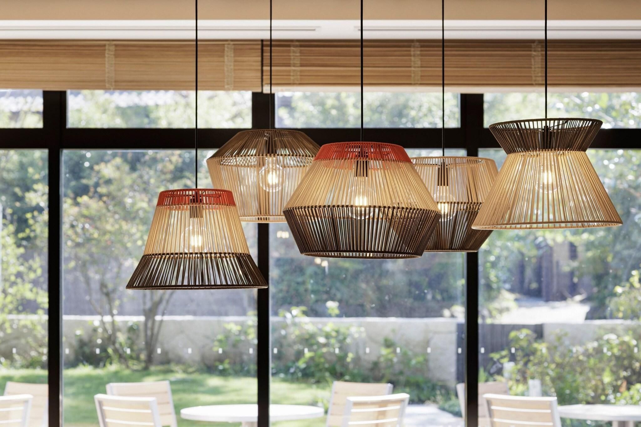 A modern interior with multiple hanging pendant lights and a view of a garden through large windows.