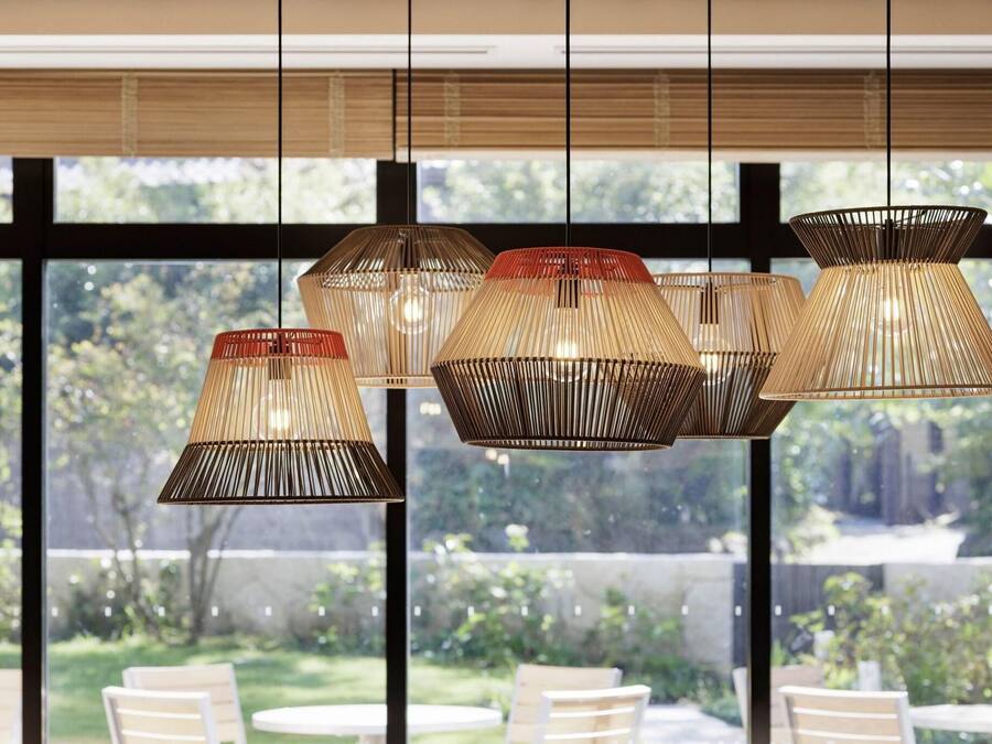 A modern interior with multiple hanging pendant lights and a view of a garden through large windows.