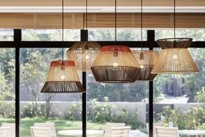 A modern interior with multiple hanging pendant lights and a view of a garden through large windows. - Fairfield By Marriott Kumamoto Aso (Aso)