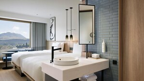 A modern hotel room with a large bed, a round sink, a mirror, and a view of a mountain. - Fairfield By Marriott Kumamoto Aso (Aso)