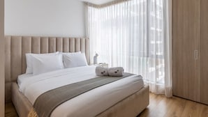 A modern hotel room with a large bed, a headboard, a nightstand, and a wardrobe.