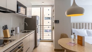 A modern kitchen with a dining area, a large window, and a view of a building outside.