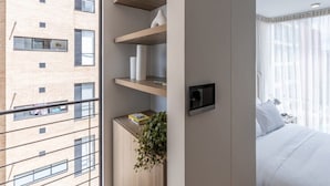 A modern hotel room with a balcony, a bed, and a wall-mounted TV.
