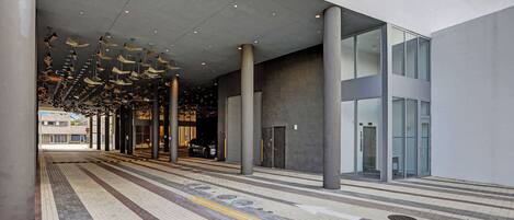 A modern building entrance with a tiled floor, directional arrows, and a glass door.
