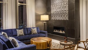 Un salon moderne avec un canapé bleu, une table basse ronde en bois et une cheminée.