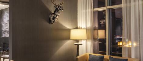 A modern living room with a sofa, two armchairs, a coffee table, and a decorative deer head on the wall.
