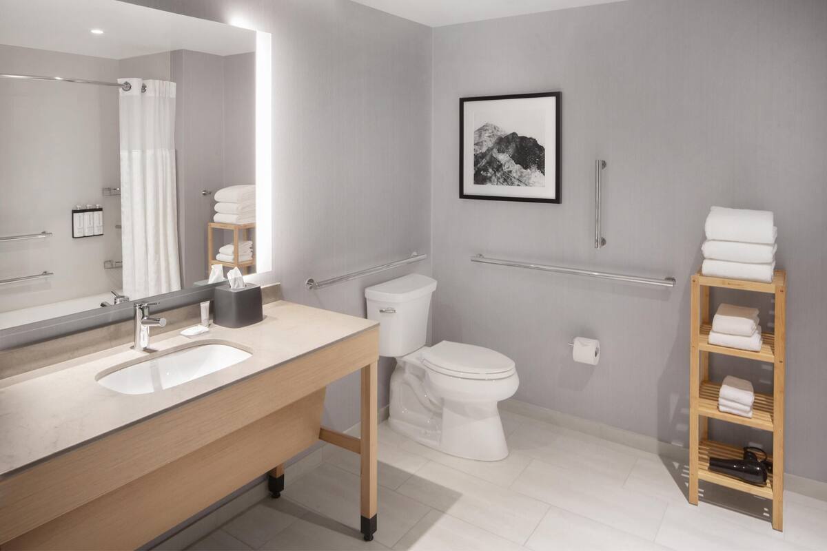 A modern bathroom with a large mirror, a sink, a toilet, and a shower area.