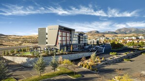 Un hôtel moderne, reconnaissable à son grand panneau « Hyatt Place », entouré d’un parking et d’espaces verts aménagés.