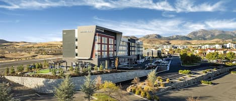 A modern hotel with a prominent 'Hyatt Place' sign, surrounded by a parking lot and landscaped areas.