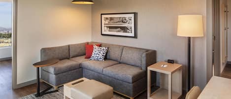 Una sala de estar moderna con un sofá seccional gris, una mesita de madera, una lámpara de pie y un cuadro en la pared.