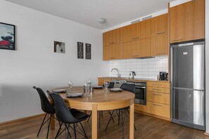 Una cocina moderna con armarios de madera, un refrigerador de acero inoxidable y una mesa de comedor para cuatro personas.