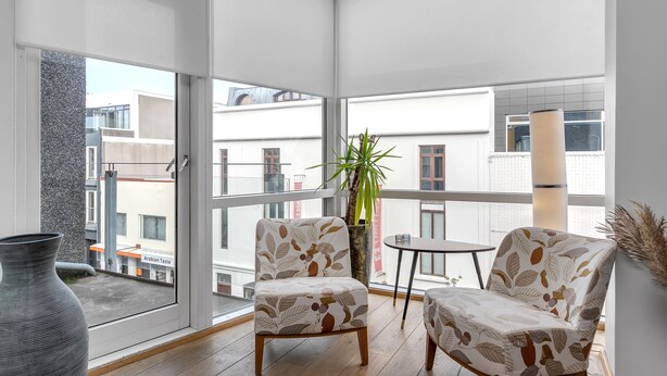A balcony with two chairs, a small table, and a potted plant.