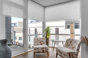 Un balcon avec deux chaises, une petite table et un pot de fleurs.