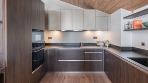 Una cocina moderna con armarios de madera oscura, una campana extractora de acero inoxidable y techo de madera.