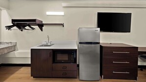 Une cuisine compacte équipée d’un four à micro-ondes, d’un réfrigérateur et d’un meuble en bois.