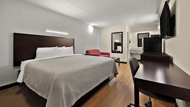 Une chambre d’hôtel avec un grand lit, un bureau, une chaise, une télévision et un miroir.