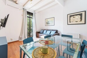 A modern living room with a glass dining table, blue chairs, a sofa with blue cushions, and a framed artwork on the wall. - Perfect for Families and Work Stays! (Barcelona)
