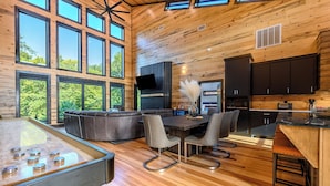 A spacious living area with a pool table, leather sofa, and dining table with chairs. - Riverfront Modern Cabin/Pickle Ball/Slide/Shuffleboard/Outdoor Shower (Eagletown)