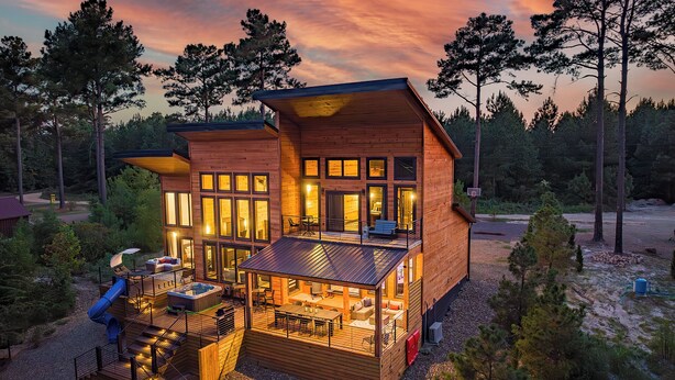 A wooden cabin with a deck, outdoor seating, and a hot tub. - Riverfront Modern Cabin/Pickle Ball/Slide/Shuffleboard/Outdoor Shower (Eagletown)