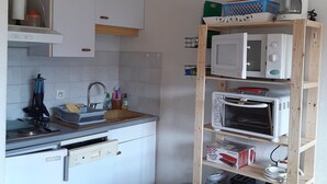 A compact kitchen with white cabinets, a built-in microwave, a toaster, and a coffee maker on a wooden shelf. - Studio cabin in Villard-de-Lans, south balcony, parking, ski locker (Villard-de-Lans)