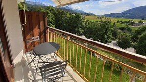 A balcony with a table and chairs, offering a view of a green valley and mountains. - Studio cabin in Villard-de-Lans, south balcony, parking, ski locker (Villard-de-Lans)