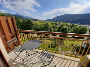 A balcony with a table and chairs, offering a view of a green valley and mountains. - Studio cabin in Villard-de-Lans, south balcony, parking, ski locker (Villard-de-Lans)