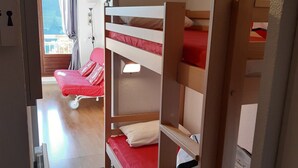 A room with bunk beds, a red chair, and a window with curtains. - Studio cabin in Villard-de-Lans, south balcony, parking, ski locker (Villard-de-Lans)