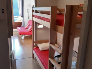 A room with bunk beds, a red chair, and a window with curtains.