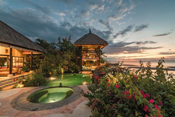 Relax by the serene pool surrounded by lush greenery and vibrant flowers.