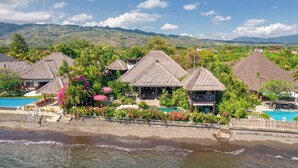 Un resort con bungalós de techo de paja, piscina y vista al mar.