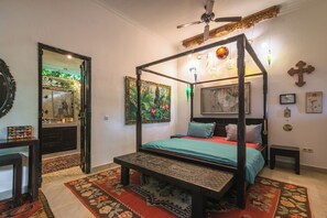 A four-poster bed with a bench, a mirror, and artwork on the walls. - Villa Kupu Kupu Tulip (Banjar)
