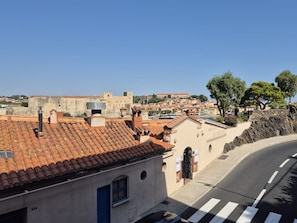 Vista de la calle con un edificio que tiene techo de tejas, una puerta azul y un letrero que dice 'RESTAURANT LE NEPTUN'.
