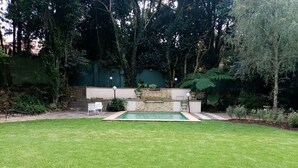 Een achtertuin met een zwembad, een stenen muur en een zitgedeelte met stoelen.