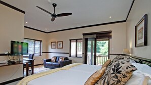 Een hotelkamer met een bed, een bureau met een computer, een stoel, een televisie en een balkon met uitzicht.