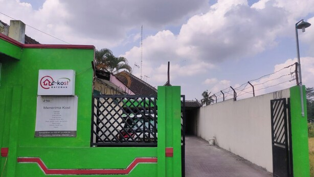 A gated entrance with a green wall and a sign for 'Menerima Kost'. - Ekost Bayeman (Sleman)