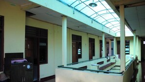 A corridor with a glass ceiling, tiled floor, and a bench along the wall. - Ekost Bayeman (Sleman)